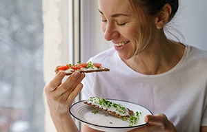 Woman smiling while eating snack at home