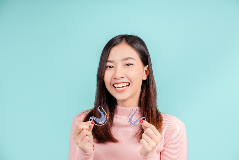 Patient smiling as they hold their retainer