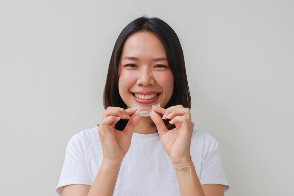 Woman smiling while holding clear aligner